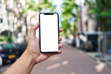Elinde akıllı telefon tutan adam sokakta beyaz beyaz ekran gösteriyor