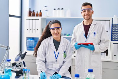 Man and woman wearing scientist uniform using touchpad write on document at laboratory