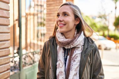 Young blonde woman smiling confident looking to the side at street