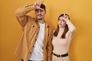 Genç İspanyol çift sarı arka planda dikiliyor. Alnında parmakları olan insanlarla dalga geçiyor. Ezik hareketler yapıyor, alay ediyor ve hakaret ediyor.. 