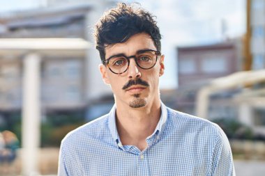 Sokakta ciddi bir ifadeyle duran beyaz bir genç.