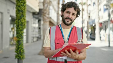 Latin kökenli genç bir adam sokak panosunda anket röportajı yazıyor.