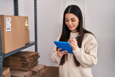 Genç, güzel, İspanyol bir kadın. İş kadını. Ofiste dokunmatik ped kullanıyor.