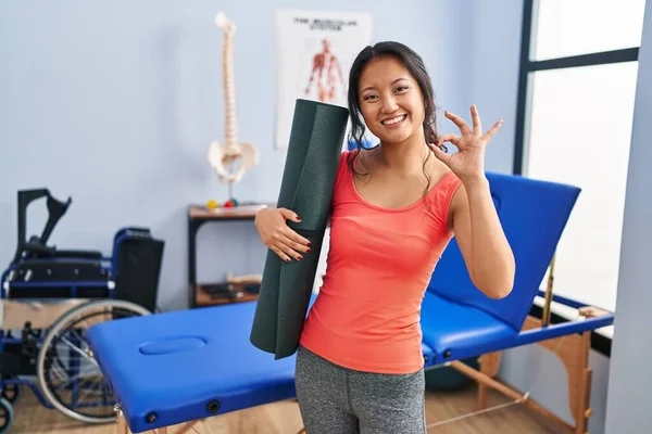 Giovane Donna Asiatica Possesso Tappetino Yoga Clinica Facendo Segno Con — Foto Stock