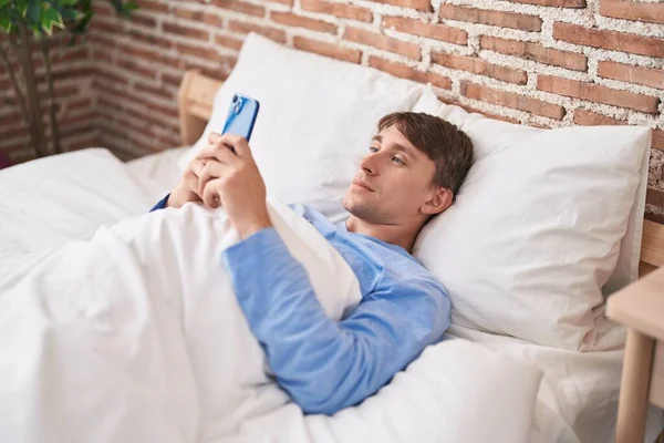 Young Caucasian Man Using Smartphone Lying Bed Bedroom — Stock fotografie