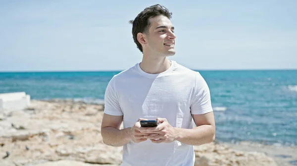 Fiatal Spanyol Férfi Mosolygós Magabiztos Segítségével Smartphone Strandon — Stock Fotó