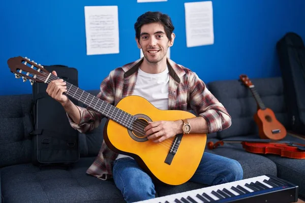 Joven Hombre Hispano Tocando Guitarra Clásica Estudio Música Mirando Positiva —  Fotos de Stock