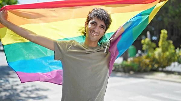 年轻的惊慌失措的男人微笑着 自信地在街上举着彩虹旗 — 图库照片
