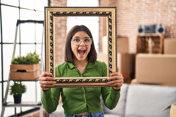 Young Hispanic Woman New Home Holding Empty Frame Celebrating Crazy — Stock Photo, Image