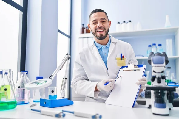 Hombre Hispano Trabajando Laboratorio Científico Sosteniendo Portapapeles Blanco Sonriendo Riendo — Foto de Stock