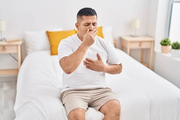 Stock image Young latin man sitting on bed yawning at bedroom