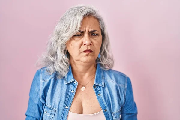 ピンクの背景懐疑的で神経の上に立っている灰色の髪を持つ中年の女性は 問題のために動揺を眉をひそめて 否定的な人 — ストック写真