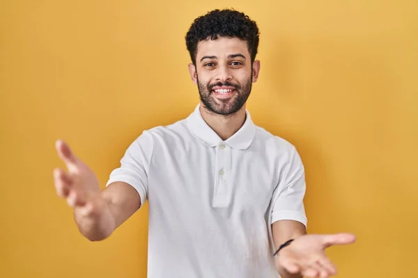 Arabische Man Staat Gele Achtergrond Glimlachend Vrolijk Het Aanbieden Van — Stockfoto