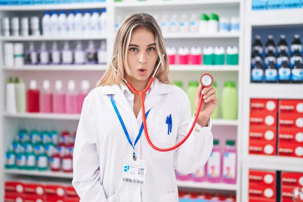 Junge Blonde Frau Arbeitet Apotheke Mit Stethoskop Verängstigt Und Erstaunt — Stockfoto