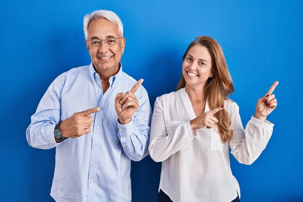 Medelåldern Latinamerikanskt Par Står Över Blå Bakgrund Ler Och Tittar — Stockfoto