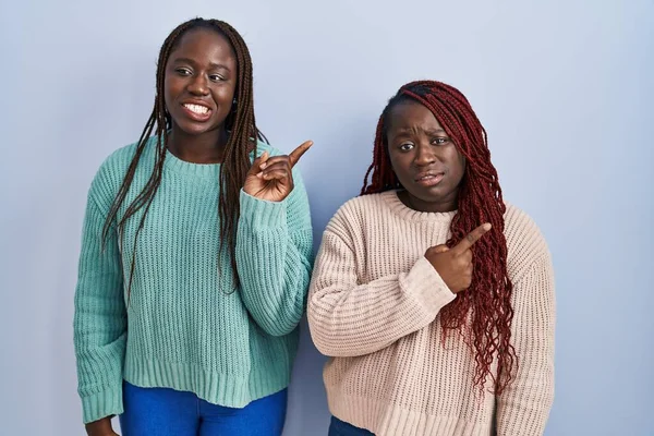 Две Африканки Стоят Синем Фоне Указывая Сторону Взволнованный Нервный Указательным — стоковое фото