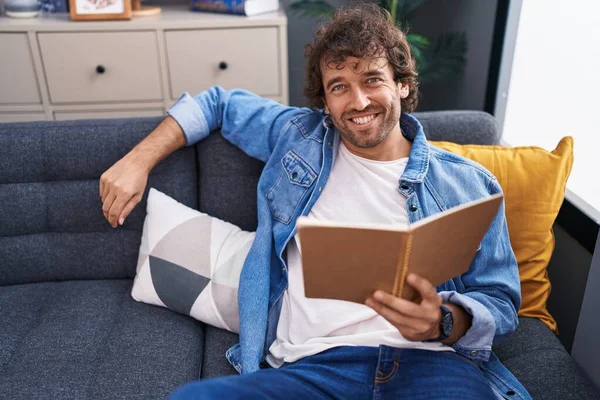 Young Hispanic Man Reading Book Sitting Sofa Home — Stock Photo, Image