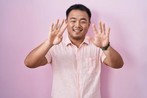 Китайский Молодой Человек Стоит Розовом Фоне Показывая Показывая Пальцами Номер — стоковое фото