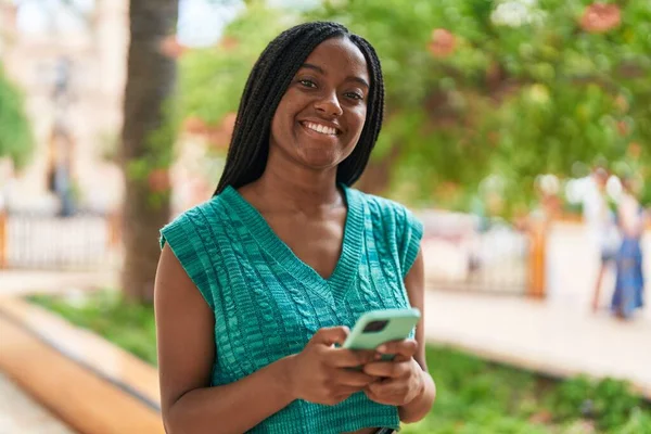 アフリカ系アメリカ人女性が公園でスマートフォンを使って自信を持って笑っている — ストック写真