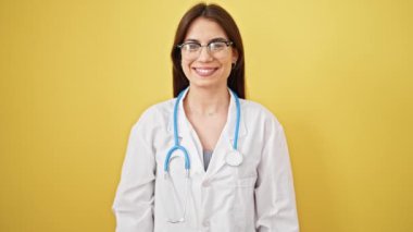 Genç, güzel İspanyol kadın doktor. Kendine güvenen, izole sarı arka planda duran.