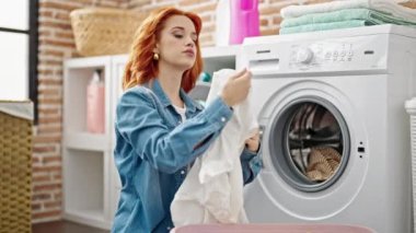 Çamaşır odasında el hareketi yapan genç kızıl saçlı kadın.