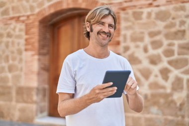 Sokakta dokunmatik ped kullanan, kendine güvenen genç sarışın adam.