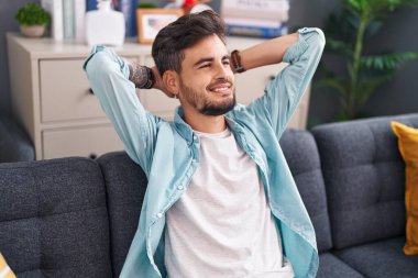 Genç İspanyol adam, ellerini başının üstüne koyup evinde kanepede oturarak rahatladı.