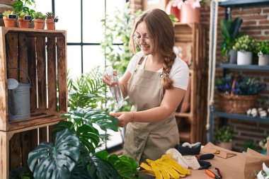 Çiçekçide su karıştırıcı kullanan genç sarışın kadın.