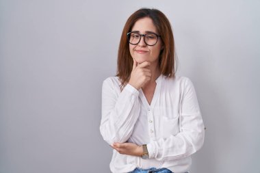 Esmer kadın izole edilmiş beyaz arka planda duruyor kameraya bakıyor kolları çapraz ve çenesi havada gülümsüyor. Olumlu düşünmek. 