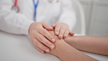 Klinikte el ele destek olan iki kadın doktor ve hasta.