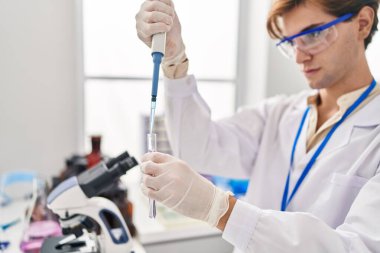 Young caucasian man scientist pouring liquid on test tube at laboratory