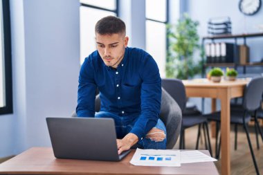 Young hispanic man business worker using laptop working at office