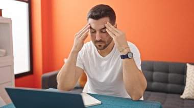 Yemek odasında dizüstü bilgisayar kullanan genç bir İspanyol.