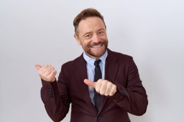 Orta yaşlı, sakallı ve kravatlı bir iş adamı. Arka tarafı işaret ediyor. El ve baş parmakları havada, kendinden emin. 