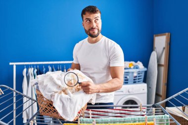 Yakışıklı İspanyol adam elinde büyüteçle kıyafetlere bakıp gülümseyen ve kafasını çeviren.. 