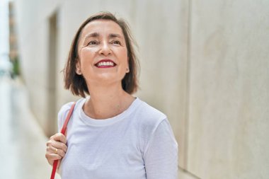 Orta yaşlı bir kadın sokakta gökyüzüne bakarak kendine güveniyor.