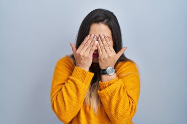 Young hispanic woman standing over isolated background rubbing eyes for fatigue and headache, sleepy and tired expression. vision problem 