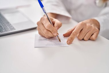 Genç, güzel İspanyol kadın doktor klinikte kartın üzerine yazıyor.