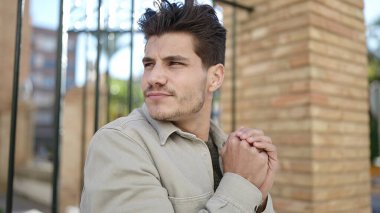 Genç İspanyol adam sokağın ortasında soğuktan ellerini ovalıyor.