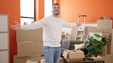 Young hispanic man smiling confident standing with arms open at new home