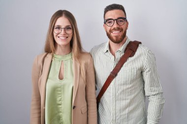 Yüzlerinde mutlu ve havalı bir gülümsemeyle beyaz arka planda duran genç bir çift. şanslı kişi. 