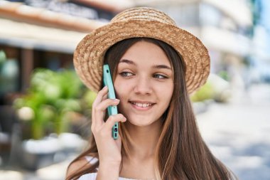 Sevimli kız turist gülümseyerek caddede akıllı telefondan konuşuyor.