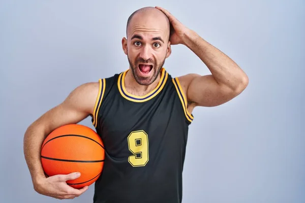 年轻的秃头男子 留着胡子 身穿篮球服 抓球疯狂 双手放在头上 害怕而且惊讶地张开嘴 — 图库照片