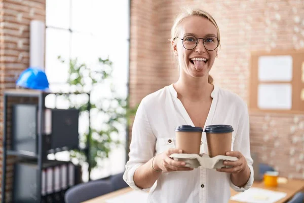 若いですCaucasian女性仕事でオフィス開催コーヒーカップステッキング舌アウト幸せとともに面白い式 — ストック写真