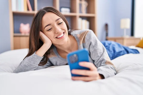 Yatakta Uzanmış Akıllı Telefon Kullanan Genç Güzel Spanyol Kadın — Stok fotoğraf