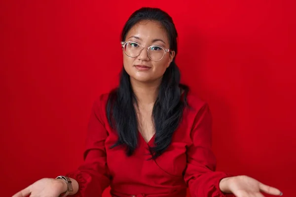Azjatycka Młoda Kobieta Stojąca Nad Czerwonym Tłem Nieświadoma Zdezorientowana Otwartymi — Zdjęcie stockowe