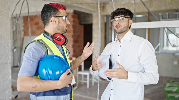 stock image Two men builder and architect standing together speaking at construction site