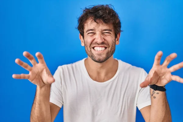 Іспанський Молодий Чоловік Стоїть Над Синім Фоном Посміхається Кумедно Роблячи — стокове фото