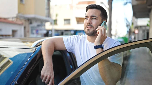 Ung Latinamerikan Man Talar Smartphone Lutar Sig Mot Bilen Gatan — Stockfoto