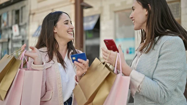 スマートフォンとクレジットカードで買い物に行く2人の女性 — ストック写真